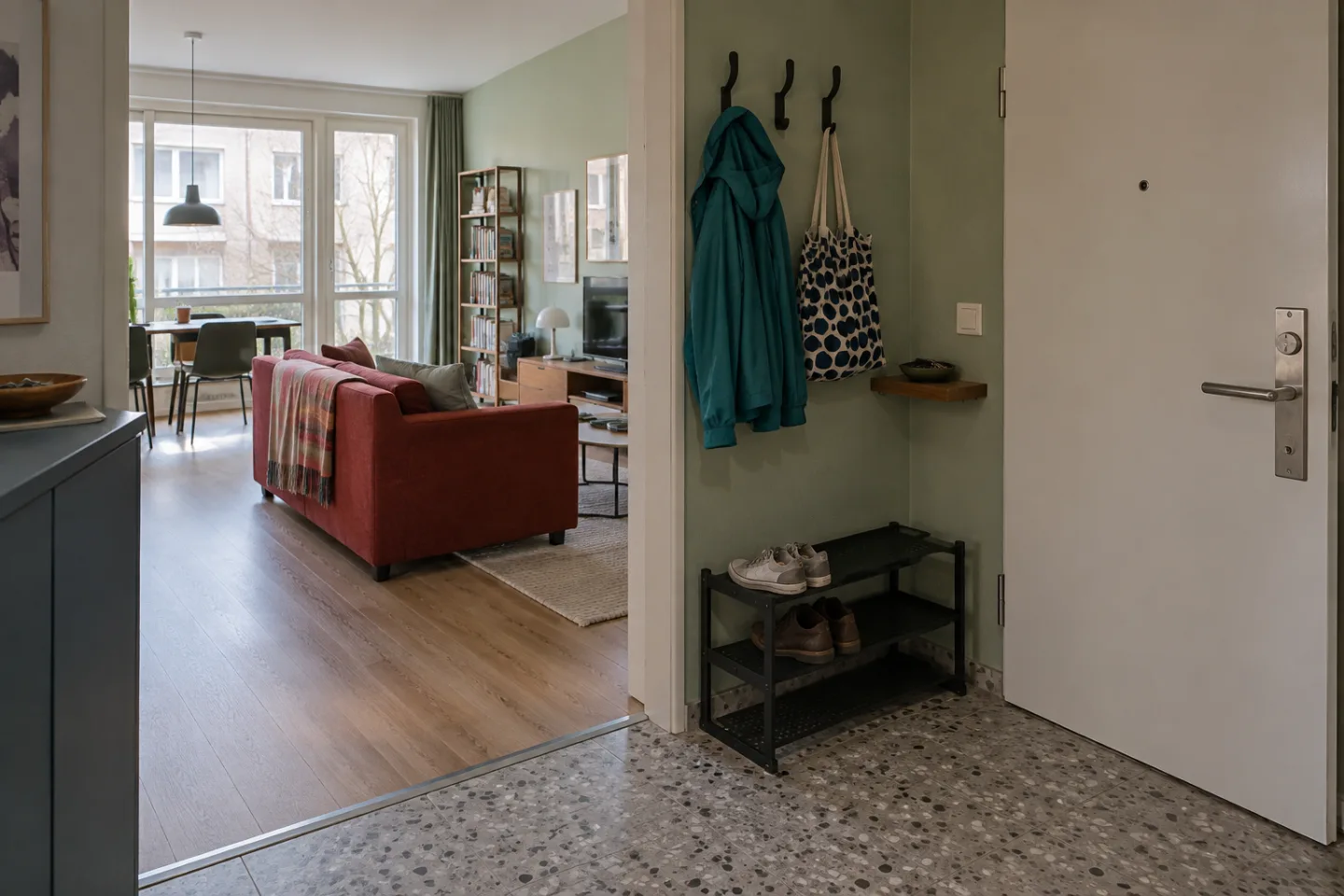 Ein kleiner Eingangsbereich neben der Wohnungstür mit Jackenhaken, Schuhablage und freiem Weg ins Wohnzimmer.