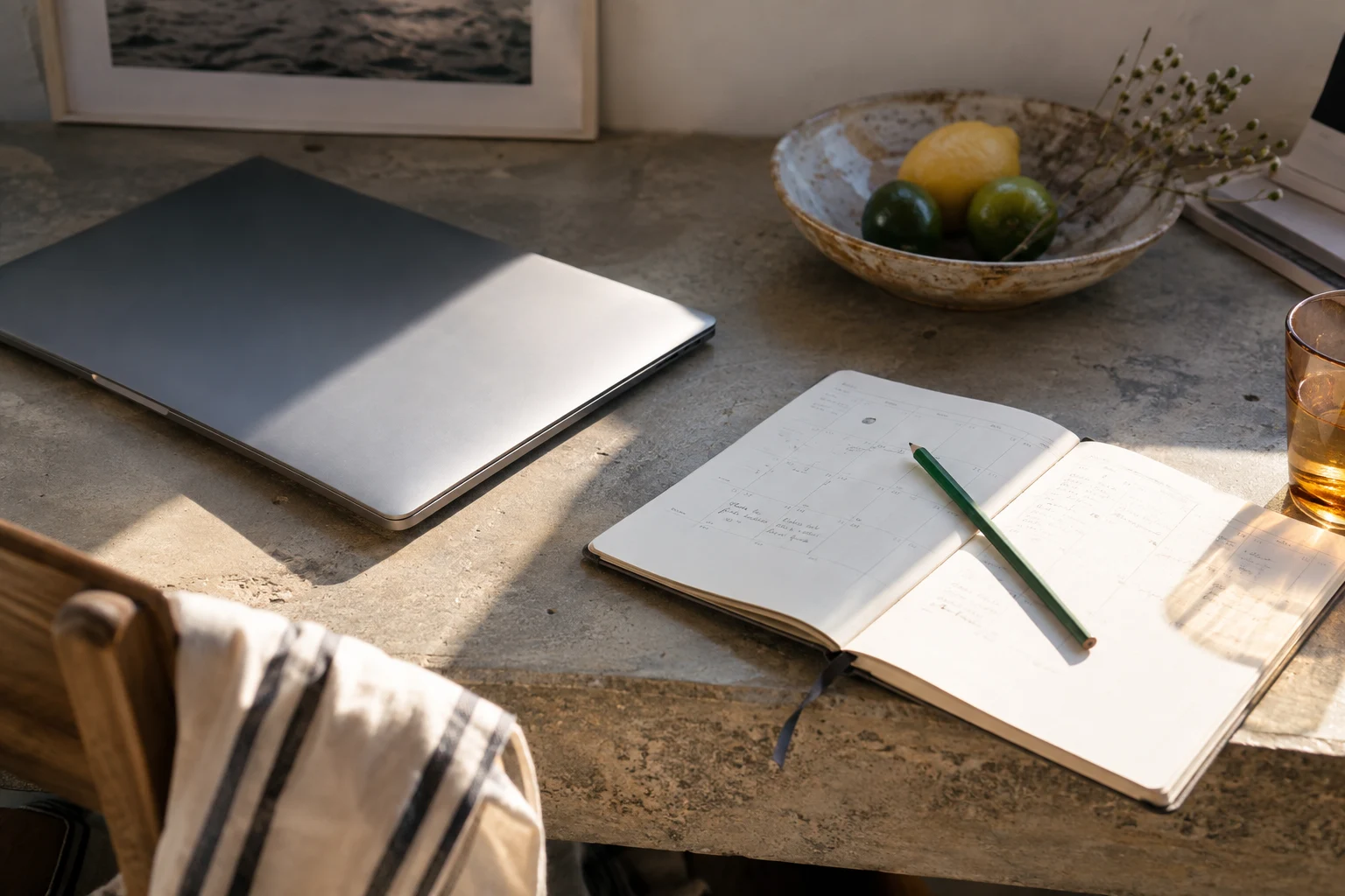 Ein geschlossener Laptop und ein Kalender liegen im geteilten Sonnenlicht.