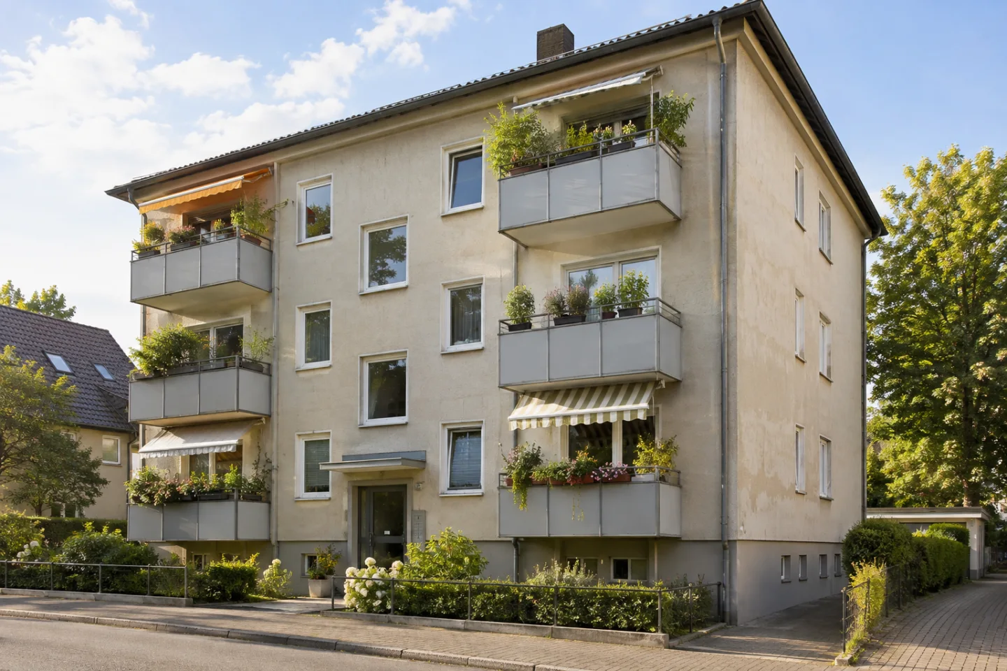 Mehrfamilienhaus mit bepflanzten Balkonen und sichtbaren Gebrauchsspuren an der Fassade.